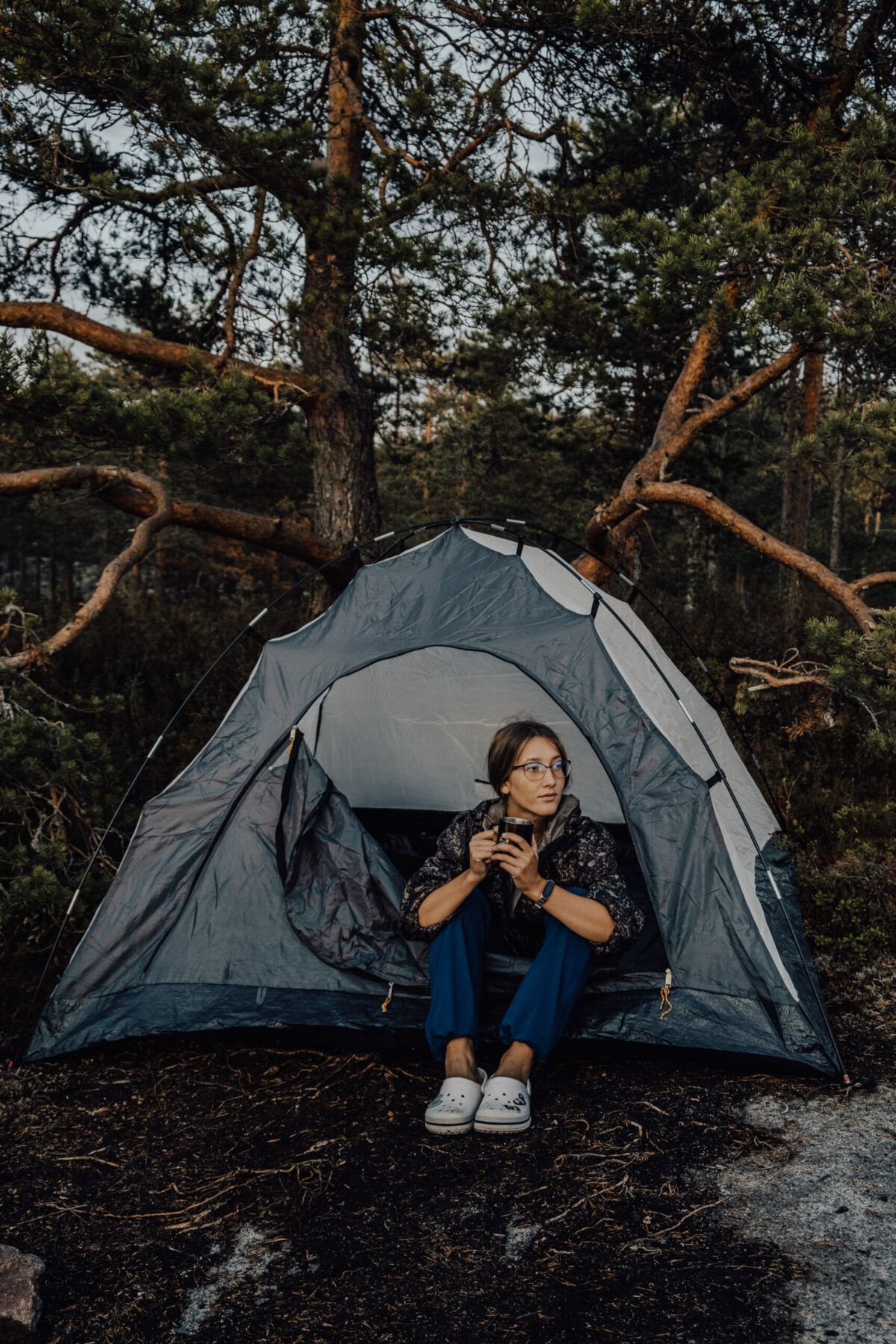 Woman sat inside her tent on a wet day drinking a hot brew