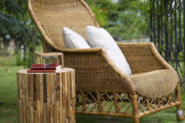 Wicker seat with pillows in the garden next to a wicker stall with books