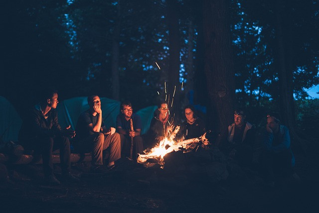 Group of people sat around a campfire at night deep in thought