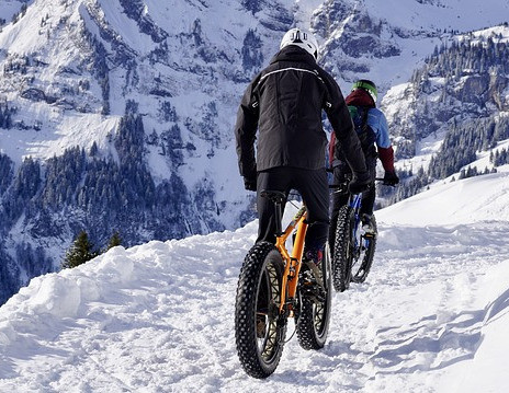 Two mountain bikers on a snowy trail in the mountains