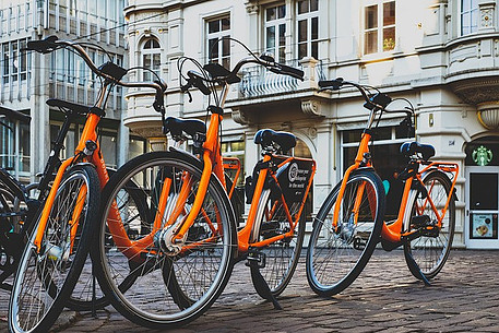 Three orange bikes on a cobbled road in the city