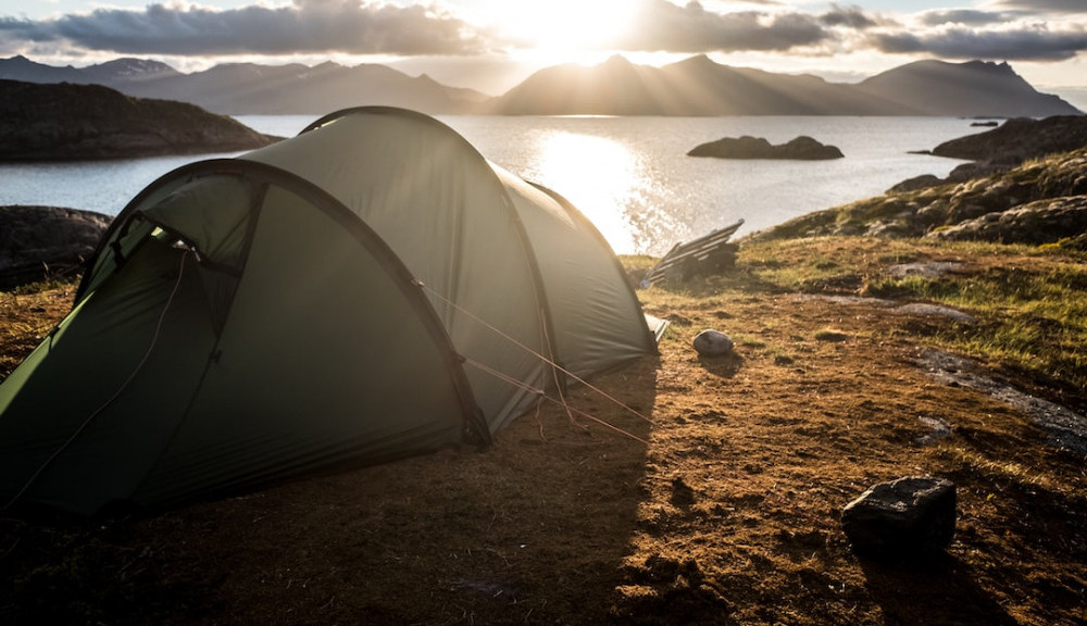 Tent pitch near a lake with a view of the island in front as the sun is going down