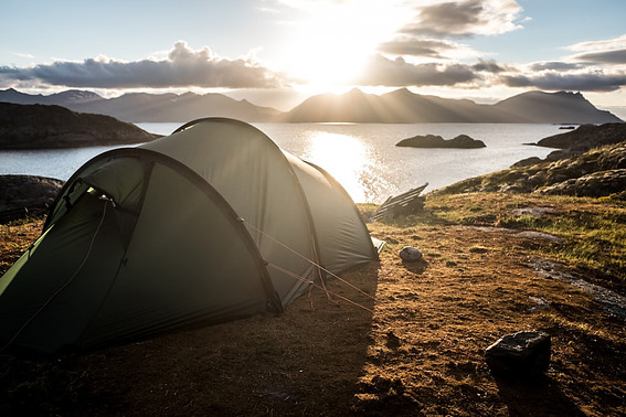 Image of a tent pitched near a lake as the sun goes down