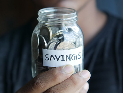 Man holding a jar of coins with the word "savings"