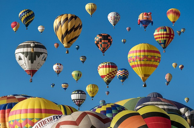 Picture of lots of colourful hot air balloons in flight on a bright sunny day and clear blue skies