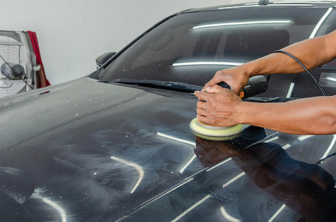 Picture of a man polishing a car with an electric buffer