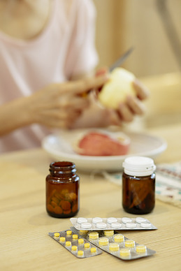 Picture of a woman preparing dinner with two bottles of weight-loss supplements in front of her