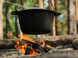 Picture of a Dutch oven hanging over a burning fire pit