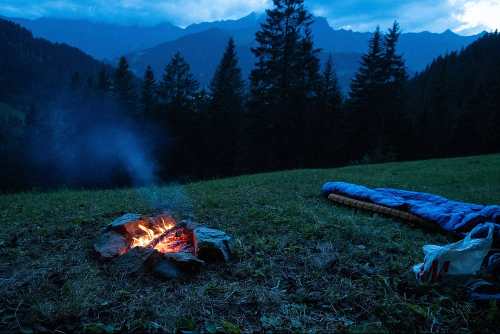 Sleeping Bag on a airbed placed on the ground with no tent next to a camp fire