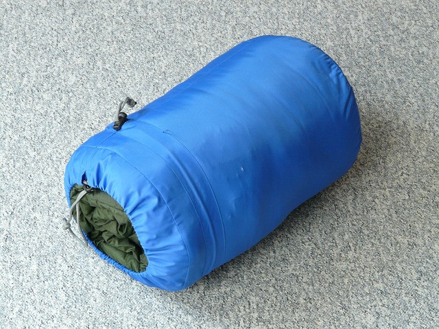 Green sleeping bag stuffed in a blue holdall