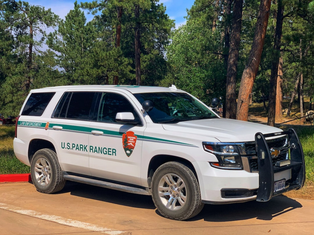 White U.S. Park Ranger vehicle parked up surrounded by trees on a bright sunny day