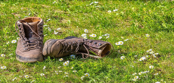 Pair of hiking boots, one upright and one laying on its side both placed on the grass