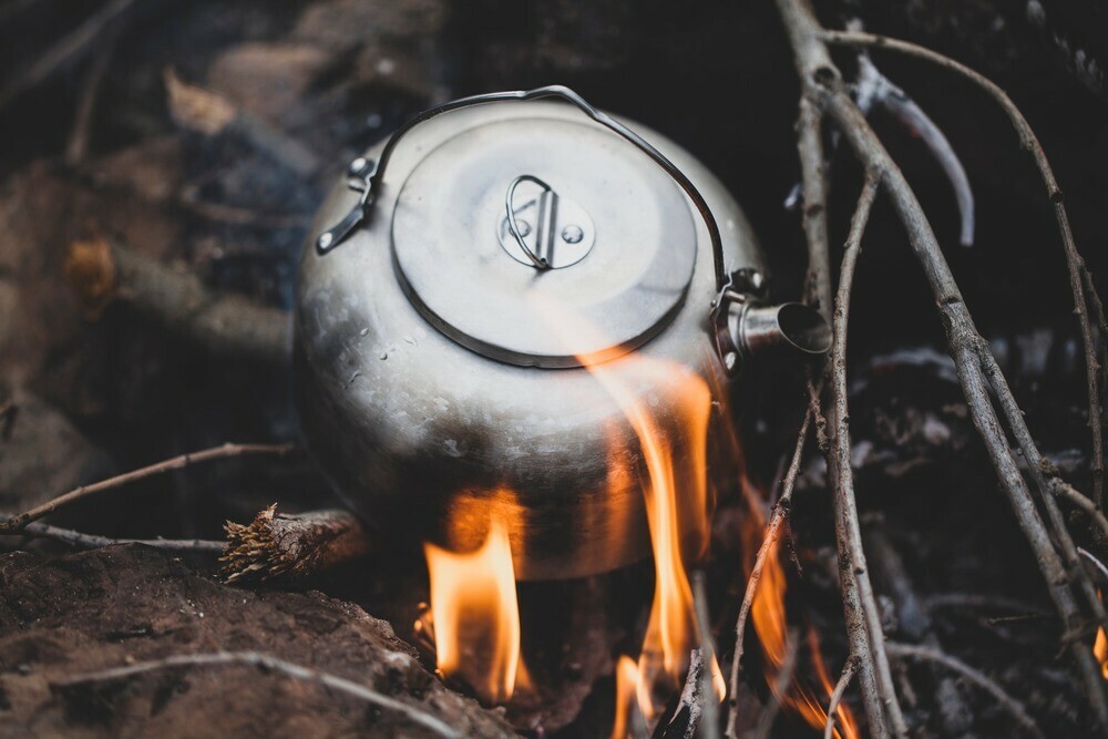 Aluminium kettle heating on a wood burning fire pit