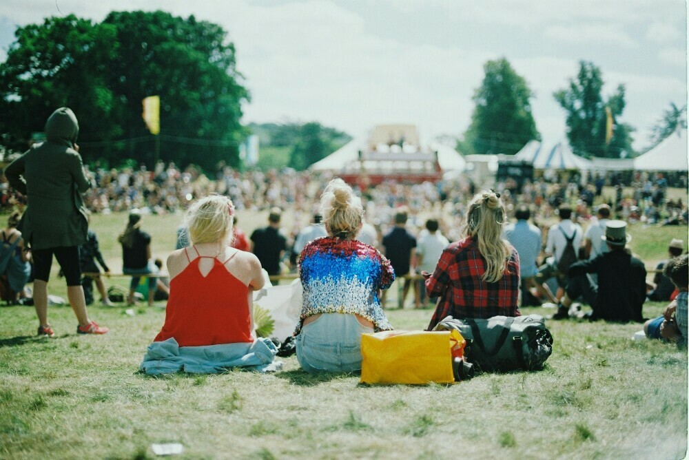 Friends sitting on the grass at a festival enjoying their day