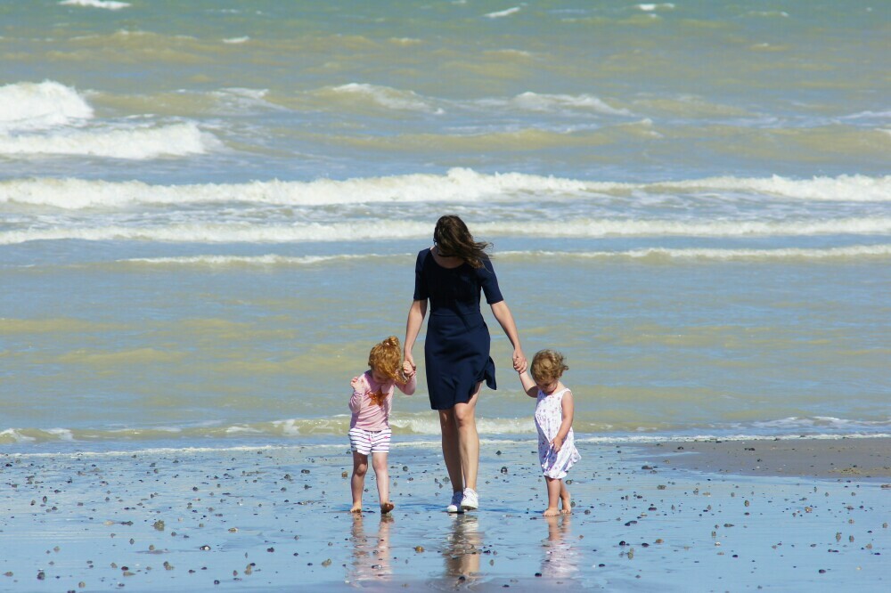 Mother and her two young children at the beach looking for crabs and shells
